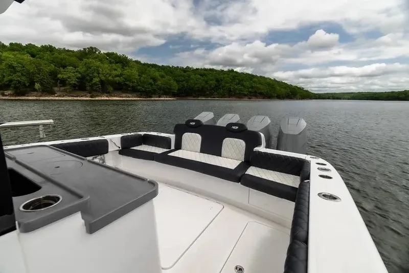 Slide: The Image of 2024 HCB 42 Lujo boat interior with seating, on a serene lake under cloudy skies. - 15