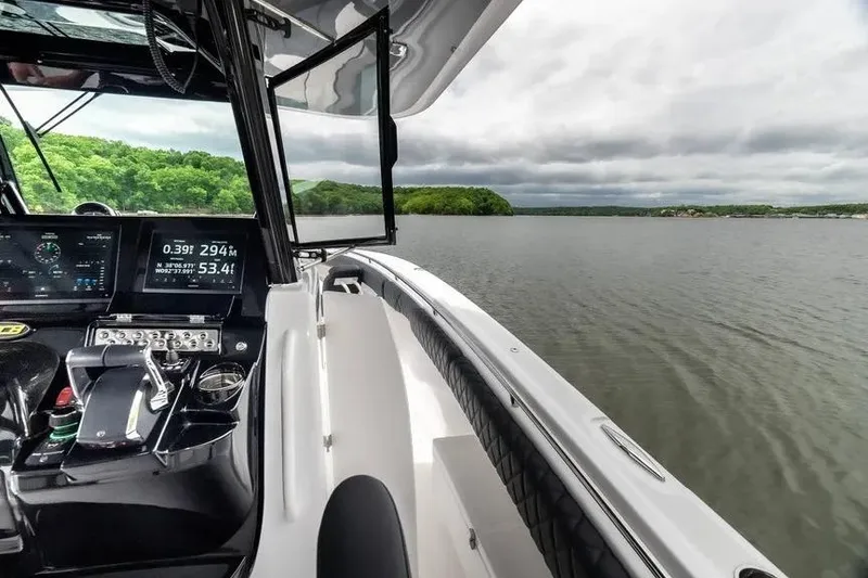 Slide: The Image of 2024 HCB 42 Lujo boat interior with navigation controls, overlooking a serene lake. - 21