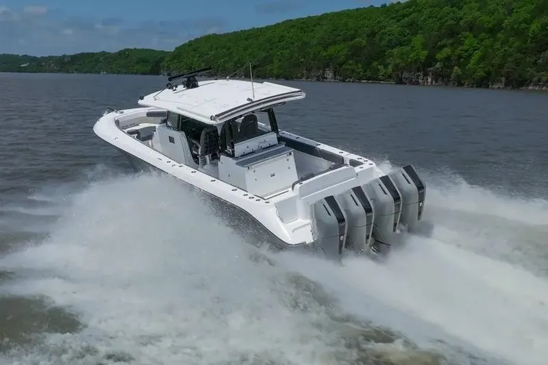 Slide: The Image of 2024 HCB 42 Lujo boat speeding on a lake with lush green shoreline. - 3