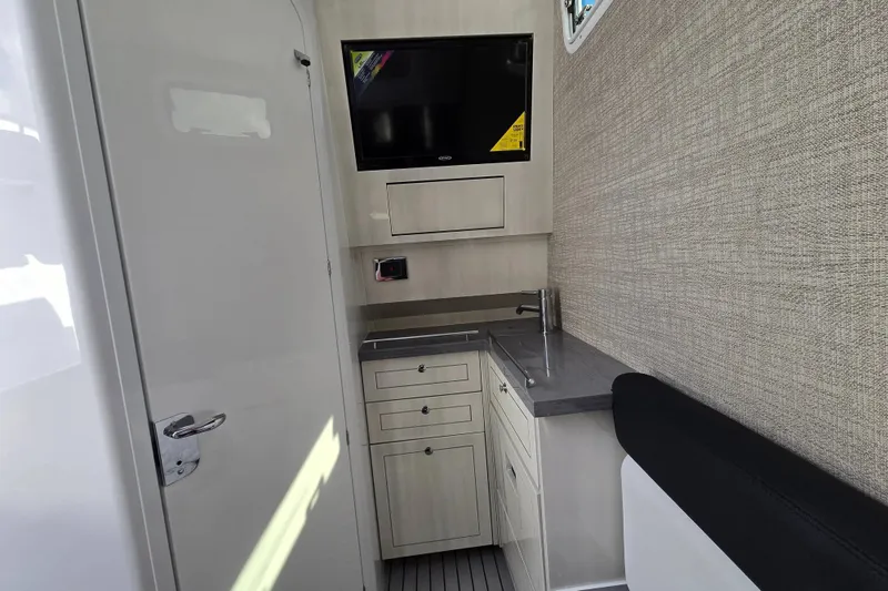 Slide: The Image of Interior of 2024 HCB 42 Lujo boat featuring a compact kitchenette and mounted TV. - 37