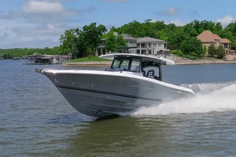 Slide: The Image of 2024 HCB 42 Lujo boat cruising on a lake near waterfront homes. - 7