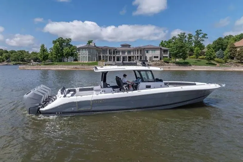 Slide: The Image of 2024 HCB 42 Lujo boat cruising on a lake near luxury waterfront homes. - 9