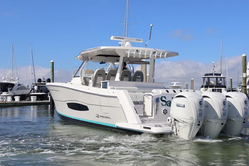 Slide: The Image of 2022 Regal 38 SAV boat with triple Yamaha engines docked in marina. - 12