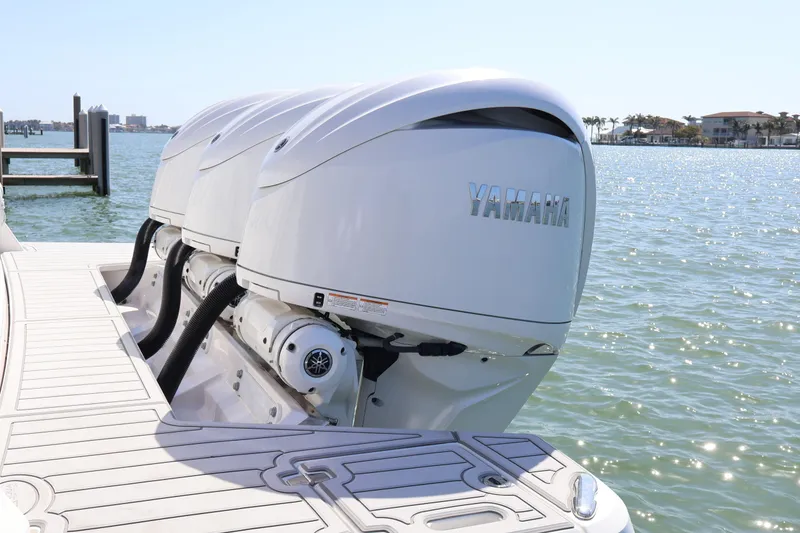 Slide: The Image of 2022 Regal 38 SAV boat docked in marina, featuring triple Yamaha engines. - 14