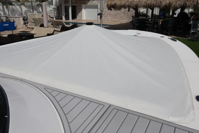 Slide: The Image of 2022 Regal 38 SAV boat with protective cover, construction site in background. - 21