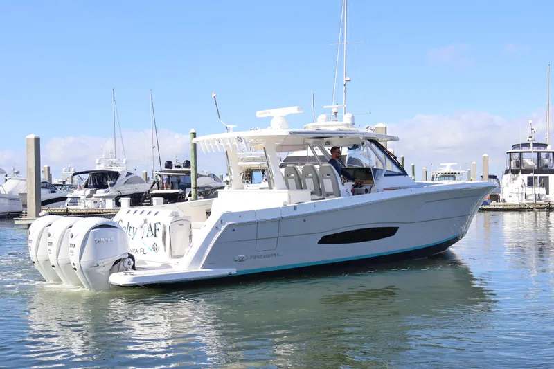 Slide: The Image of 2022 Regal 38 SAV boat docked in marina, clear sky, calm water. - 4