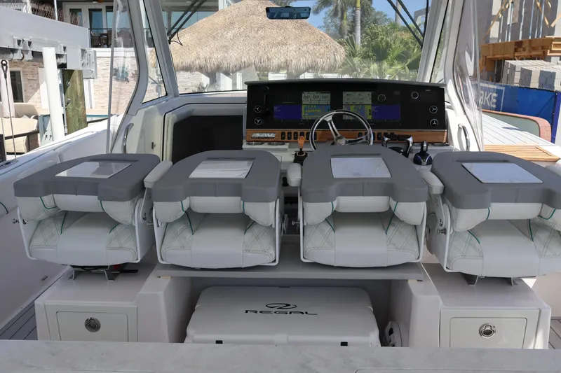 Slide: The Image of 2022 Regal 38 SAV boat cockpit with dual white captain chairs and advanced navigation system. - 57