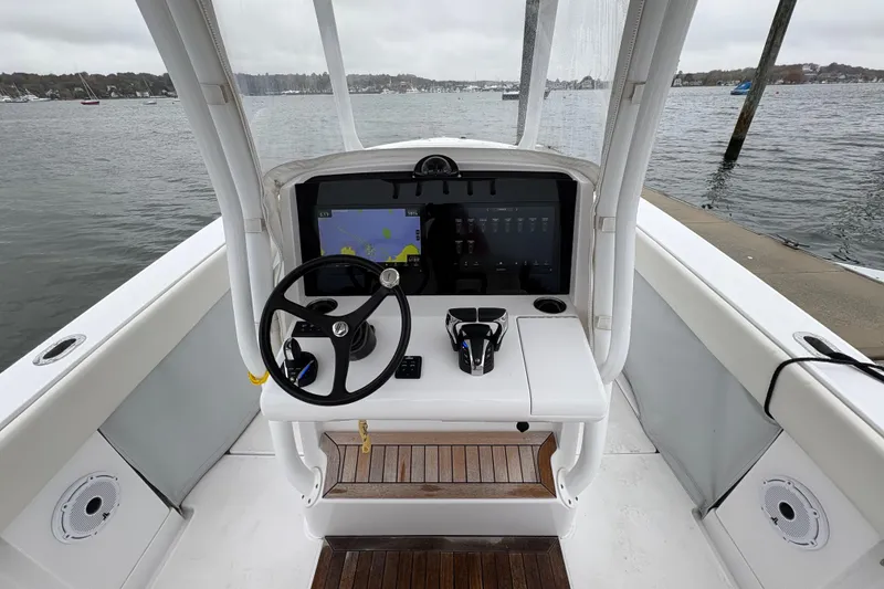 Slide: The Image of 2023 Jupiter 30 boat helm with steering wheel and navigation display on calm water. - 10