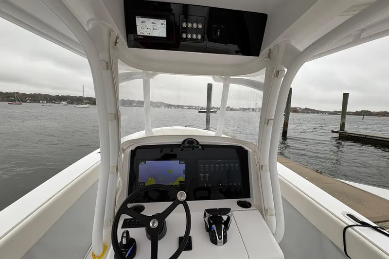 Slide: The Image of 2023 Jupiter 30 boat cockpit with advanced navigation system, steering wheel, and waterfront view. - 14