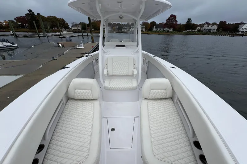 Slide: The Image of 2023 Jupiter 30 boat with white quilted seating, docked by a calm waterfront. - 20