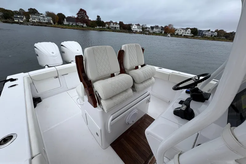 Slide: The Image of 2023 Jupiter 30 boat interior with dual seats and twin engines on a calm lake. - 23