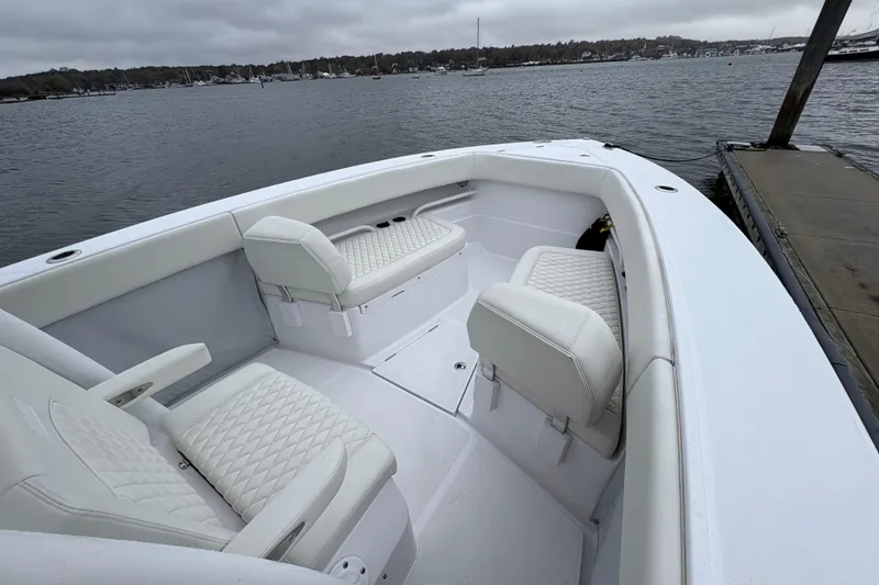 Slide: The Image of 2023 Jupiter 30 boat interior with white seating, docked by a calm waterfront. - 30