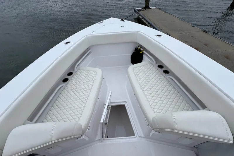 Slide: The Image of 2023 Jupiter 30 boat interior with white cushioned seating and storage compartment. - 33