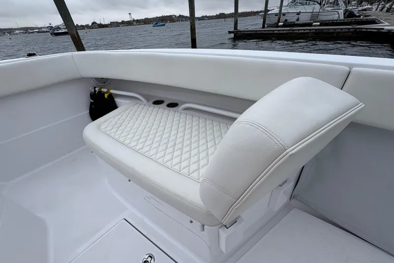 Slide: The Image of White cushioned seating on 2023 Jupiter 30 boat, docked by the water. - 35