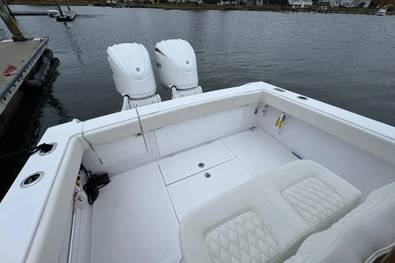 Slide: The Image of 2023 Jupiter 30 boat with dual engines, spacious deck, and white seating, docked by the water. - 36
