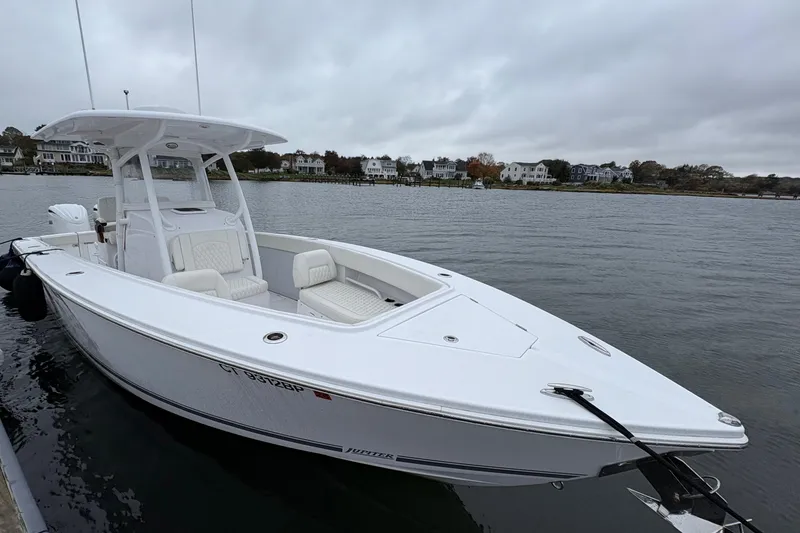 Slide: The Image of 2023 Jupiter 30 boat docked on a calm waterfront, overcast sky in the background. - 41