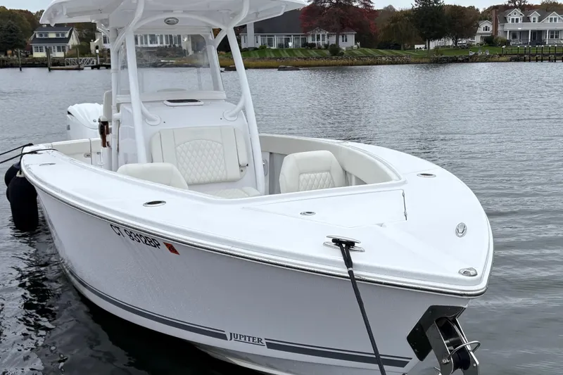 Slide: The Image of 2023 Jupiter 30 boat docked on a serene waterfront with houses in the background. - 42