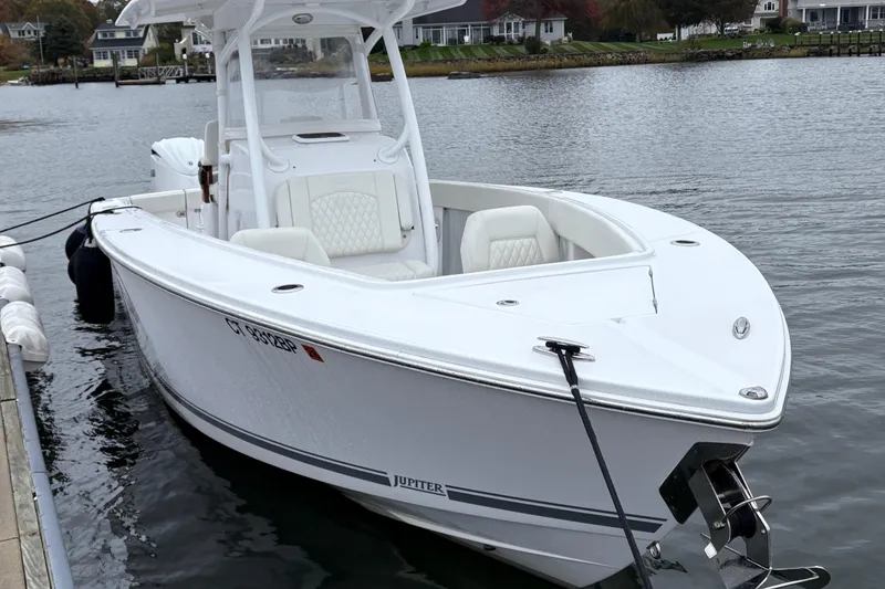 Slide: The Image of 2023 Jupiter 30 boat docked on calm water, featuring sleek design and white seating. - 43