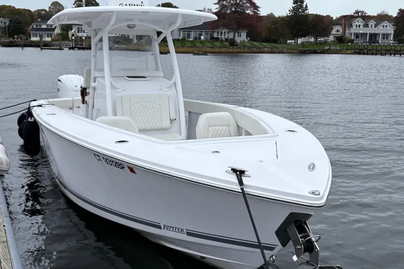 Slide: The Image of 2023 Jupiter 30 boat docked on a calm waterfront with houses in the background. - 44