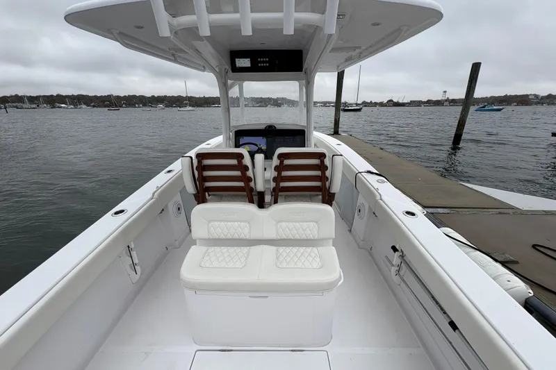 Slide: The Image of 2023 Jupiter 30 boat interior at dock, featuring white seating and open water view. - 51