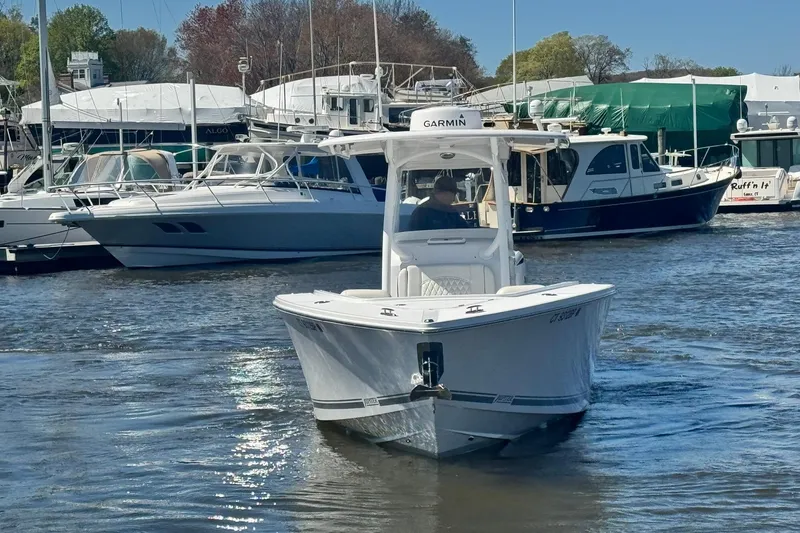 Slide: The Image of 2023 Jupiter 30 boat cruising in a marina with docked yachts in the background. - 74