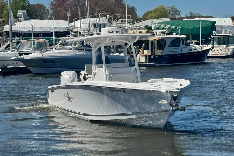 Slide: The Image of 2023 Jupiter 30 boat navigating marina waters with other vessels docked nearby. - 79