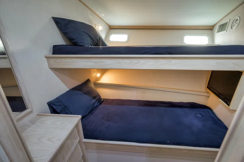 Slide: The Image of 1998 Rybovich Convertible yacht interior with cozy bunk beds and soft lighting. - 14