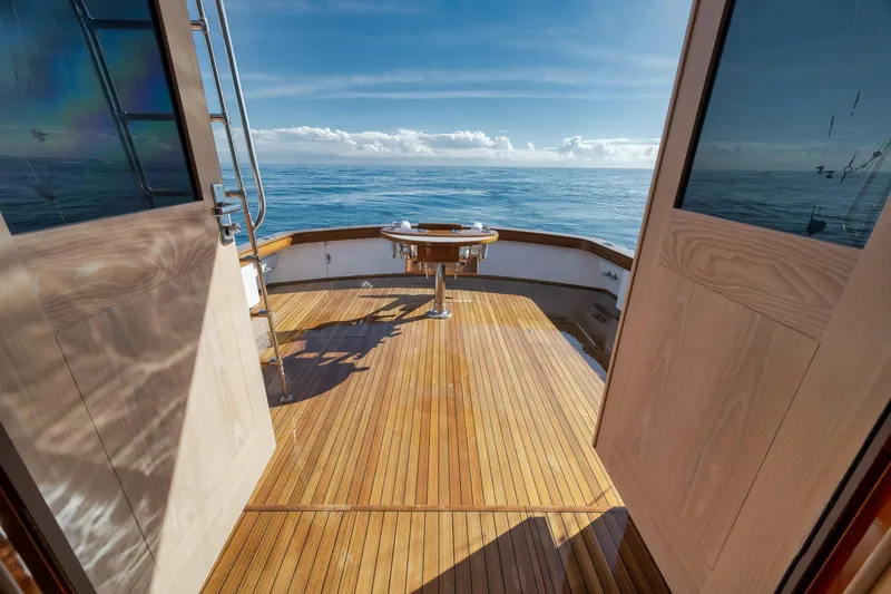 Slide: The Image of 1998 Rybovich Convertible yacht deck with ocean view, featuring wooden flooring and open doors. - 28