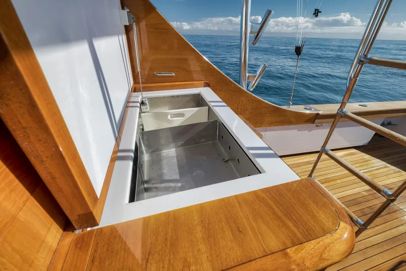 Slide: The Image of 1998 Rybovich Convertible yacht deck with open storage compartment, wooden finish, and ocean view. - 32