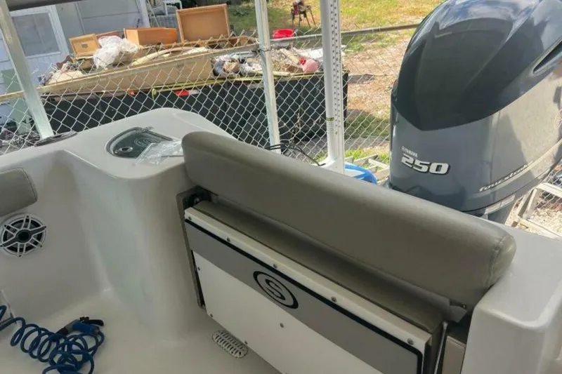 Slide: The Image of 2021 Sportsman Open 232 Center Console boat with cushioned seating in a residential driveway. - 13