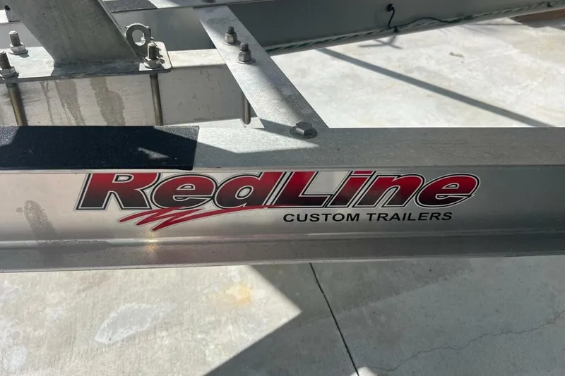 Slide: The Image of 2021 Sportsman Open 232 Center Console boat on trailer, parked near chain-link fence. - 50