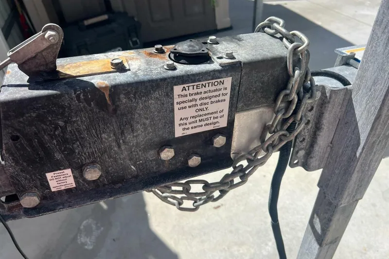 Slide: The Image of Trailer brake actuator with warning label, secured by a chain, for Sportsman Open 232 Center Console 2021. - 57