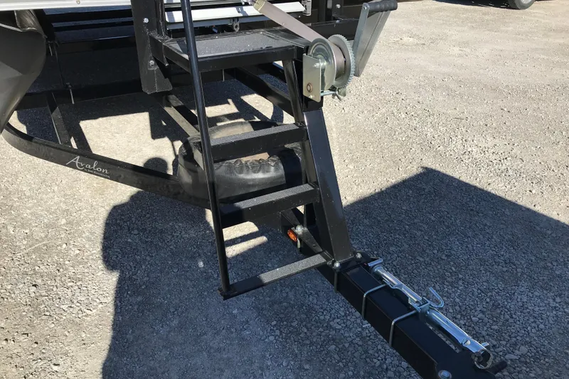 Slide: The Image of 2023 Avalon LSZ Rear Fish trailer hitch and ladder on gravel surface. - 23