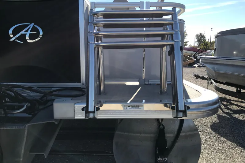 Slide: The Image of 2023 Avalon LSZ Rear Fish boat with ladder and logo, parked outdoors. - 26