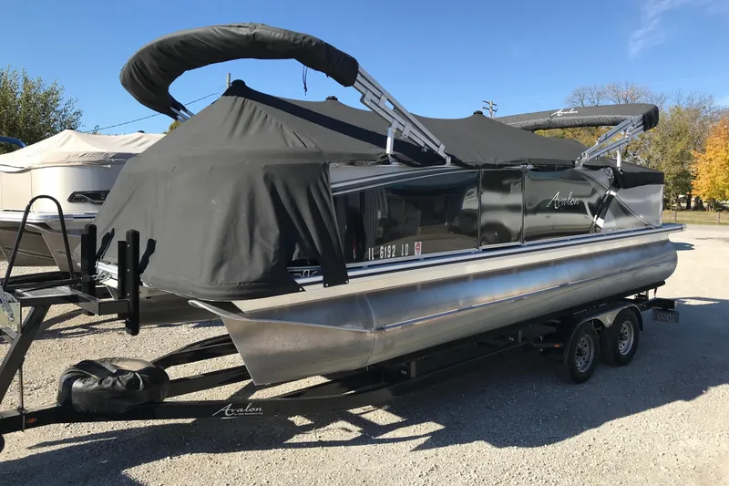 Slide: The Image of 2023 Avalon LSZ Rear Fish pontoon boat with black cover on a trailer. - 28