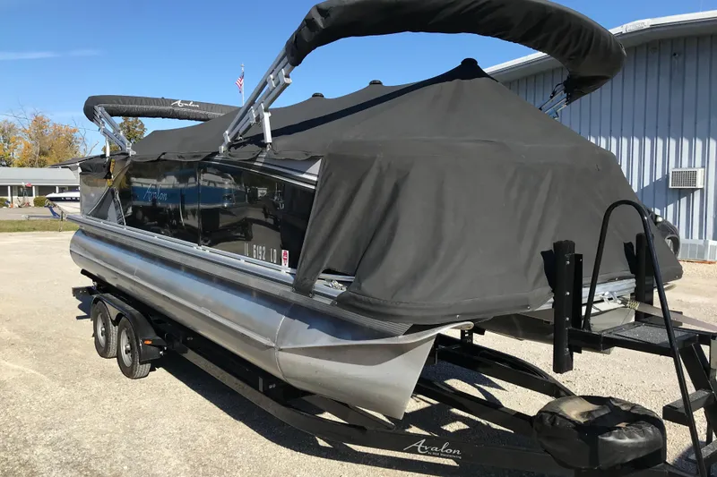 Slide: The Image of 2023 Avalon LSZ Rear Fish pontoon boat on trailer, covered and parked outdoors. - 30