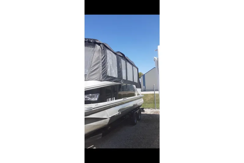 Slide: The Image of 2023 Avalon LSZ Rear Fish boat with canopy, parked outdoors under clear blue sky. - 32