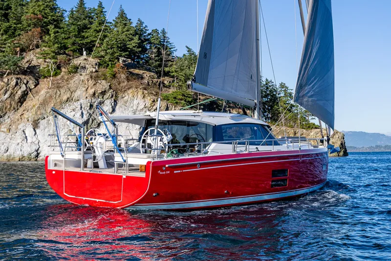 Slide: The Image of Red 2024 Moody 41ds sailboat cruising near rocky coastline with lush greenery. - 1