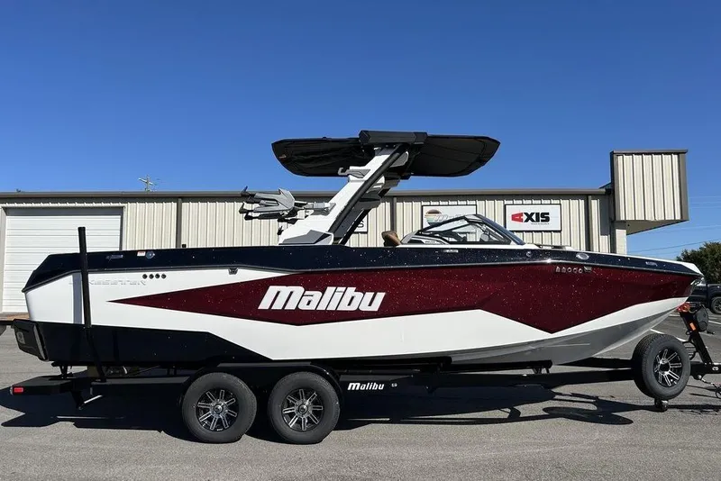 The Image of 2026 Malibu Sunscape 25 LSV boat on trailer, parked outdoors, side view. - 2