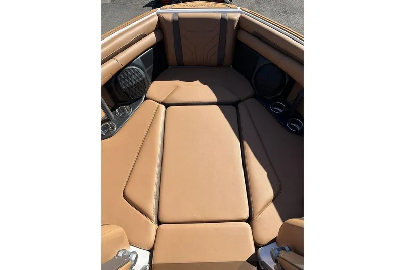 Slide: The Image of 2026 Malibu Sunscape 25 LSV boat interior with tan leather seating and cup holders. - 22