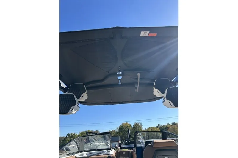 Slide: The Image of 2026 Malibu Sunscape 25 LSV boat interior with speakers and canopy under clear blue sky. - 23