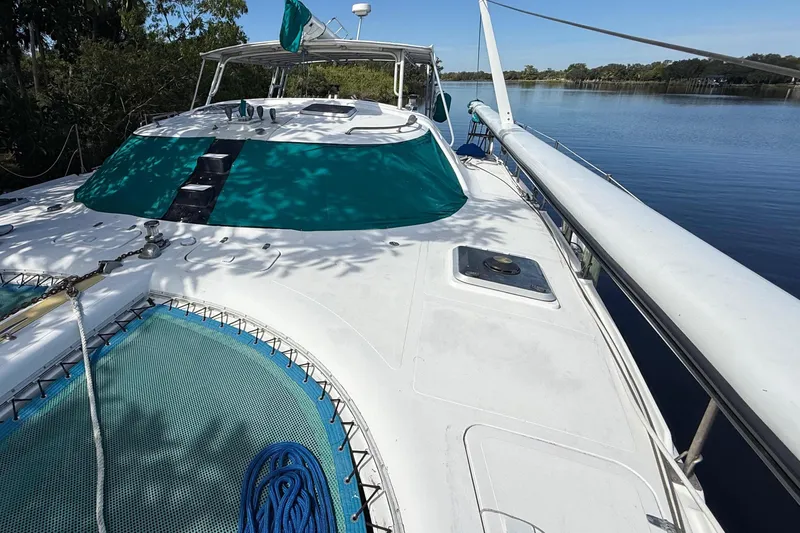 The Image of 1995 Manta Sailing Catamaran docked by a serene river under clear blue skies. - 0