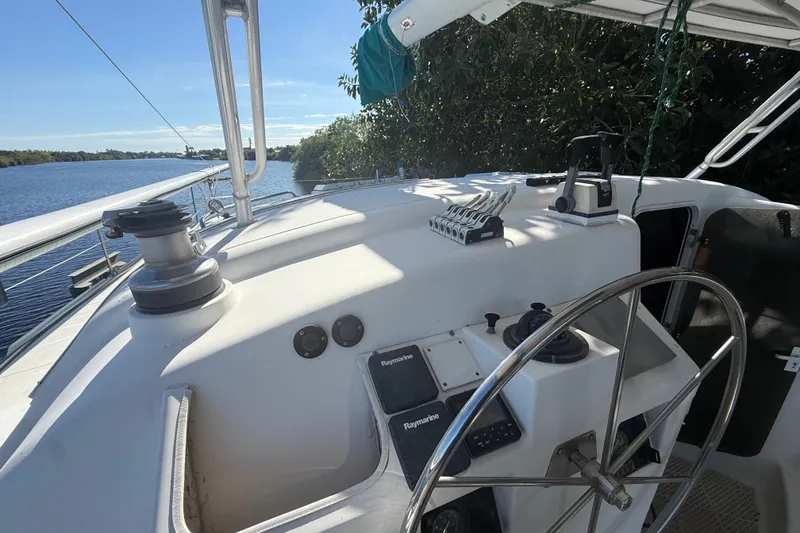 Slide: The Image of 1995 Manta Sailing Catamaran cockpit with steering wheel and navigation equipment, docked by a river. - 15