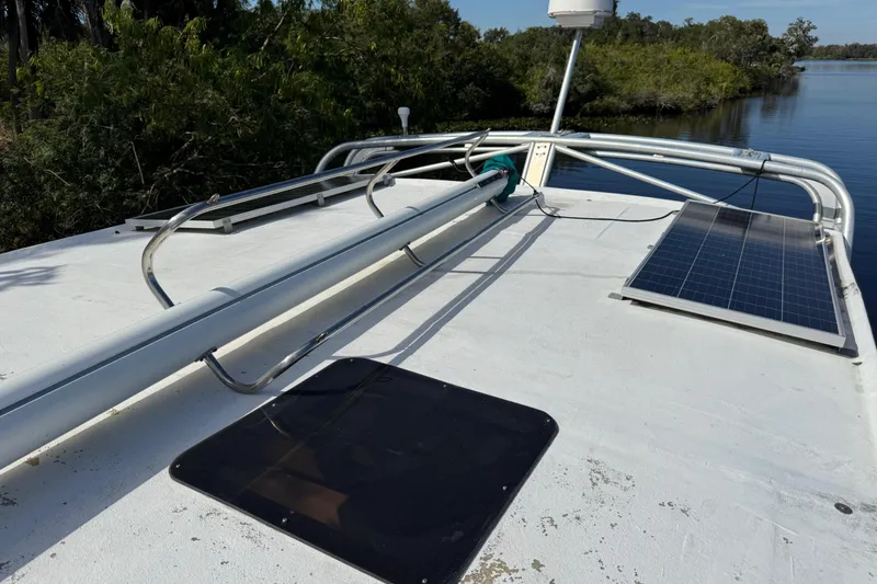 Slide: The Image of Rooftop of 1995 Manta Sailing Catamaran with solar panel and railing, near lush waterway. - 17