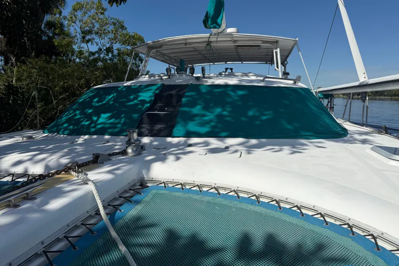 Slide: The Image of 1995 Manta SAILING CATAMARAN with green sunshade, docked near lush greenery. - 2