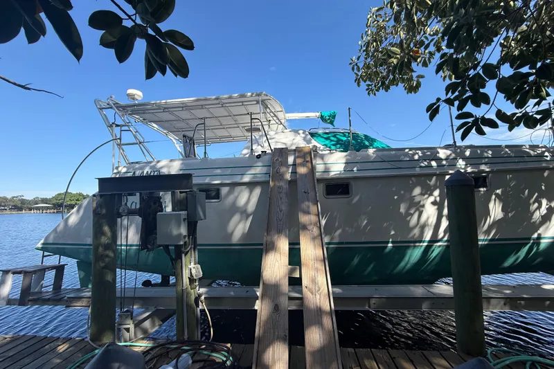 Slide: The Image of 1995 Manta Sailing Catamaran docked by a serene waterfront under clear blue skies. - 3