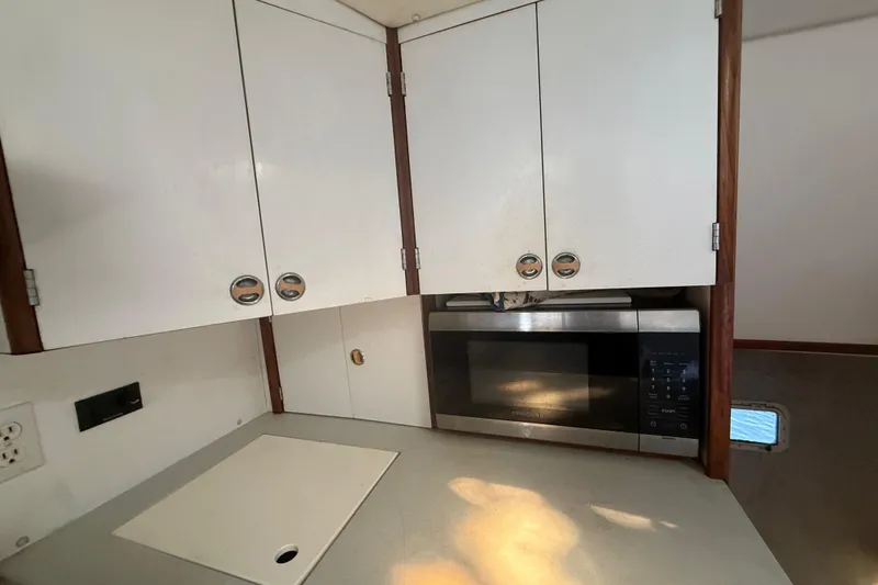 Slide: The Image of Compact kitchen area in a 1995 Manta Sailing Catamaran with microwave and white cabinets. - 31