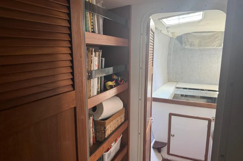 Slide: The Image of Interior of 1995 Manta Sailing Catamaran with wooden shelves and cabin doorway. - 37