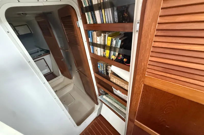 Slide: The Image of Interior of 1995 Manta Sailing Catamaran with wooden shelves and books. - 44