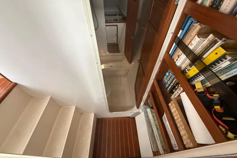 Slide: The Image of Interior of 1995 Manta Sailing Catamaran with stairs, wooden shelves, and books. - 45